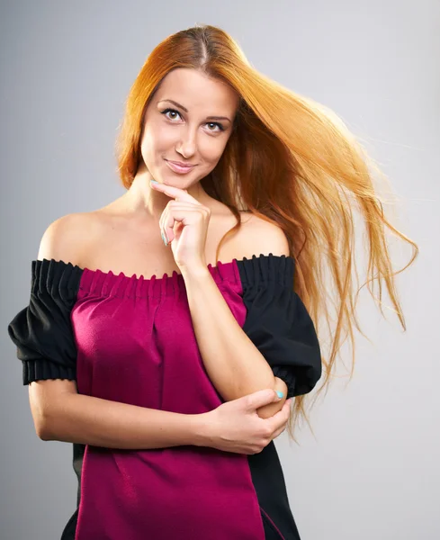 Attraktive junge Frau mit langen roten Haaren im roten Kleid. — Stockfoto