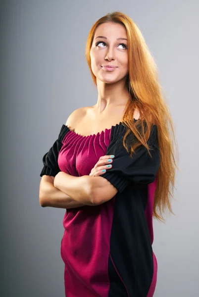 Kırmızı elbiseli uzun kızıl saçlı çekici genç kadın. — Stok fotoğraf