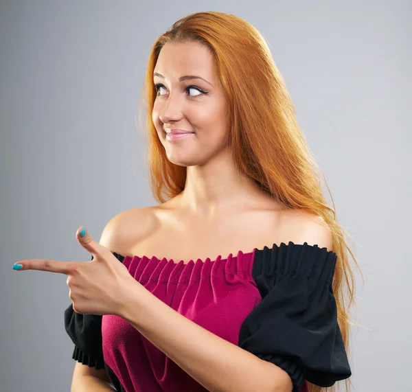 Aantrekkelijke jonge vrouw in een jurk. geeft aan haar vinger naar de r — Stockfoto