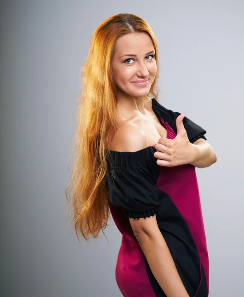 Uma jovem atraente de vestido. Mostrando polegares para cima . — Fotografia de Stock