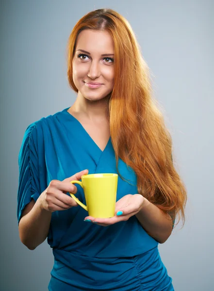 Attraktive junge Frau im blauen Kleid. hält einen gelben Becher. — Stockfoto