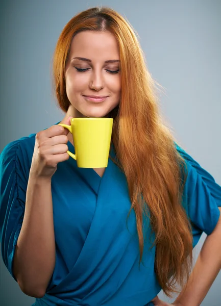 Attraktive junge Frau im blauen Kleid. hält einen gelben Becher. — Stockfoto