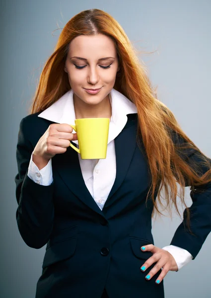 Aantrekkelijke jonge vrouw in een zwarte jas. houdt een gele kop. — Stockfoto