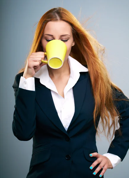 Attractive young woman in a black jacket. Drinking from yellow c — Stock Photo, Image