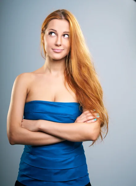 Mujer joven atractiva en una blusa azul con el pelo largo y rojo. Mira. —  Fotos de Stock