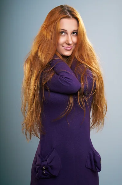 Attraktive junge Frau in fliederfarbenem Kleid. lange rote Haare. — Stockfoto