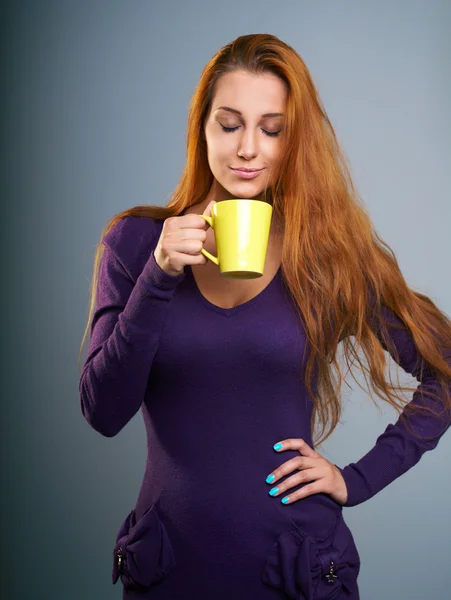 Atractiva joven con un vestido lila. Mujer sostiene un cu amarillo — Foto de Stock