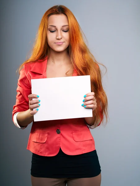 Una joven atractiva con una chaqueta roja. Sostiene un póster y mira — Foto de Stock