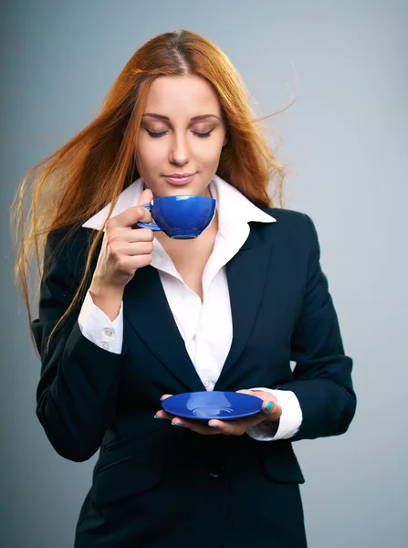 Jolie jeune femme vêtue d'une veste noire. Tient une tasse bleue et s Images De Stock Libres De Droits