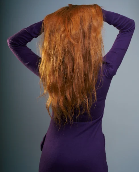 Mladá žena v purpurových šatech stojí zpět. krásné dlouhé červené ha Royalty Free Stock Fotografie