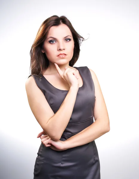 Attractive young woman in a gray business dress. Holding her fin — Stock Photo, Image