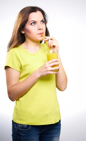 Giovane donna attraente con una camicia gialla. Bere succo d'arancia . — Foto Stock