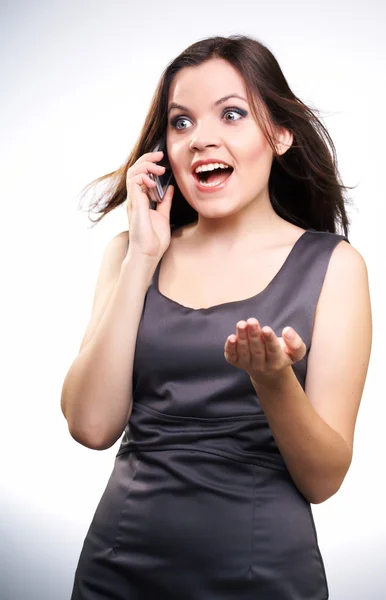 Έκπληκτος νεαρή γυναίκα σε ένα φόρεμα γκρι επιχειρήσεων. γυναίκα μιλάει στο — Stockfoto