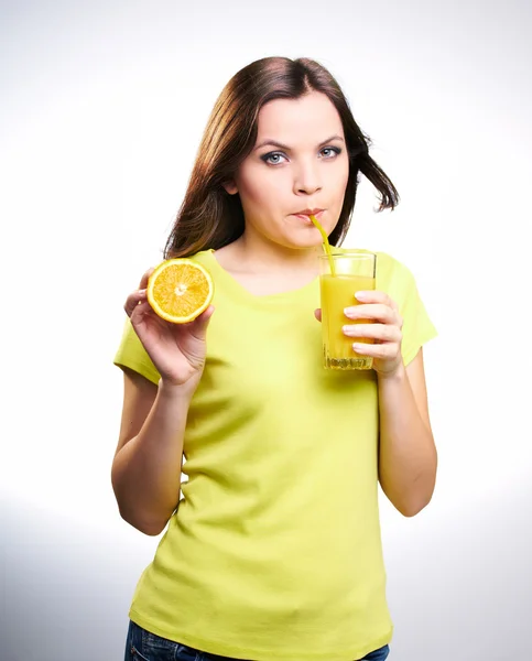 Attractive young girl in a yellow T-shirt drinking orange juice — Stock Photo, Image