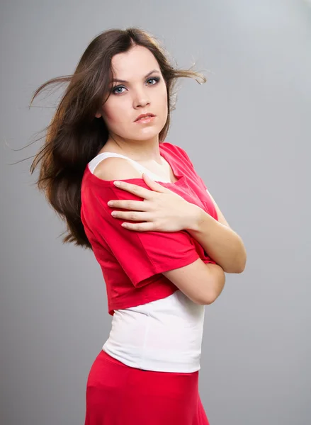 Aantrekkelijke jonge vrouw in een rode shirt en de rok. haar in beweging. — Stockfoto