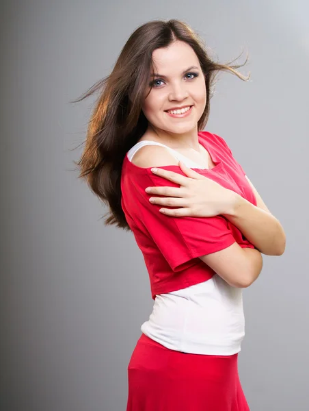 Happy young woman in a red shirt and skirt. Hair in motion. — Stock Photo, Image