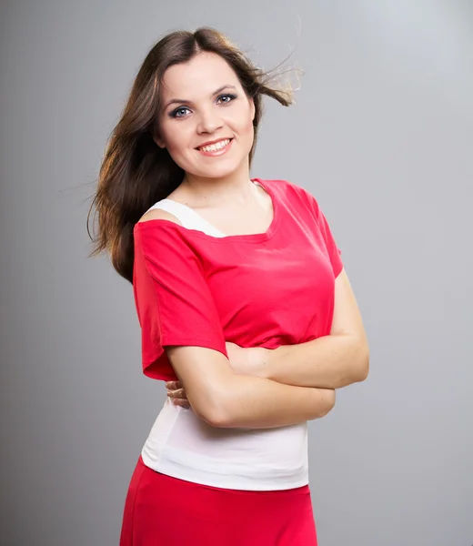 Happy young woman in a red shirt and skirt. Hair in motion. — Stock Photo, Image