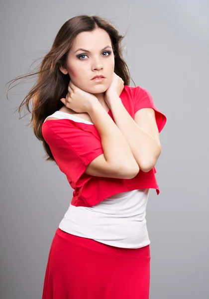 Aantrekkelijke jonge vrouw in een rode shirt en de rok. hugs haar nek. — Stockfoto