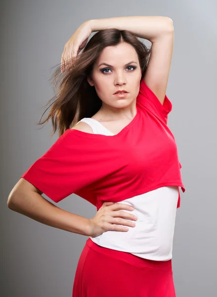 Attractive young woman in a red shirt and skirt. One hand is rai — Stock Photo, Image