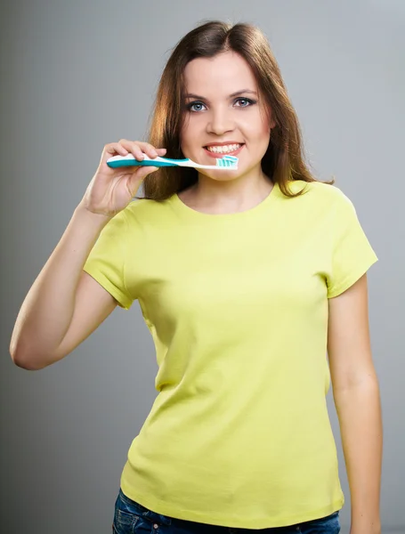 Uma jovem atraente com uma camisa amarela. Segurando uma escova de dentes w — Fotografia de Stock