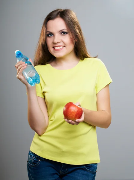 Giovane donna attraente con una camicia gialla. Contiene una mela rossa e — Foto Stock