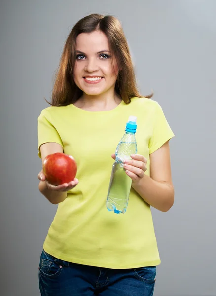 Attractive young woman in a yellow shirt. Holds a red apple and — Stock Photo, Image