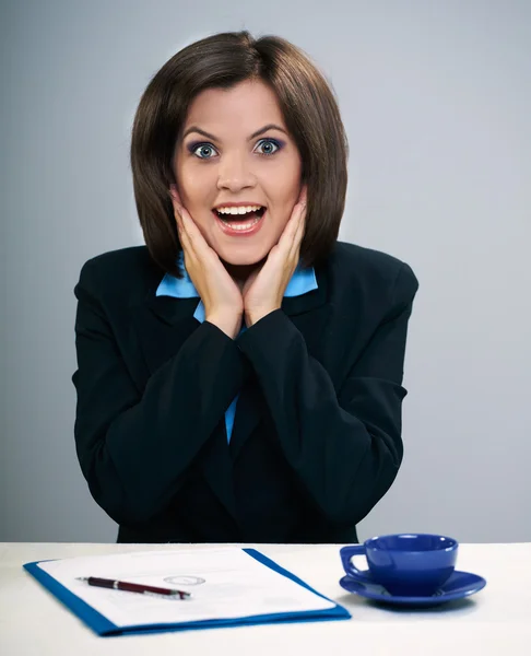 Surprised young woman in a black jacket and glasses sitting at t — Stock Photo, Image