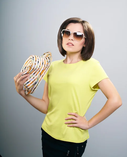 Attractive young woman in a yellow shirt and sunglasses. Holds a — Stock Photo, Image