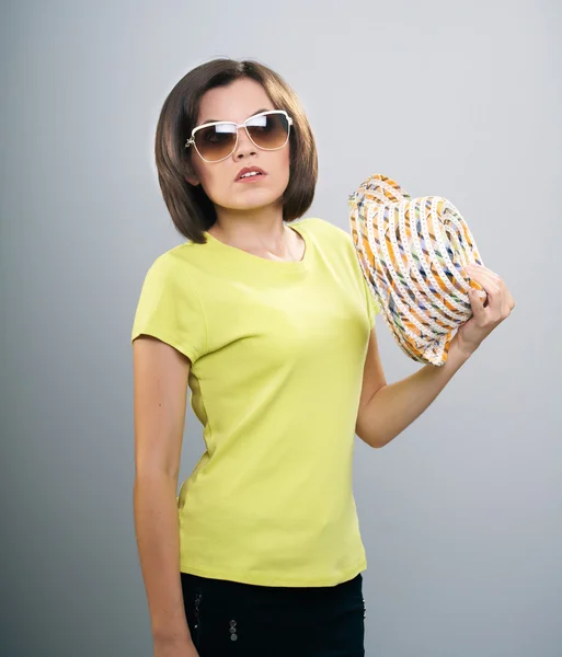 Atractiva joven con una camisa amarilla y gafas de sol. Mantiene una — Foto de Stock