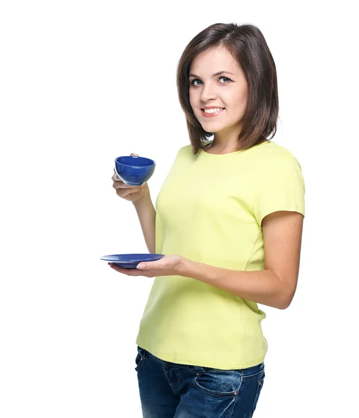 Aantrekkelijke jonge vrouw in een gele overhemd. houdt een blauw kop. — Stockfoto