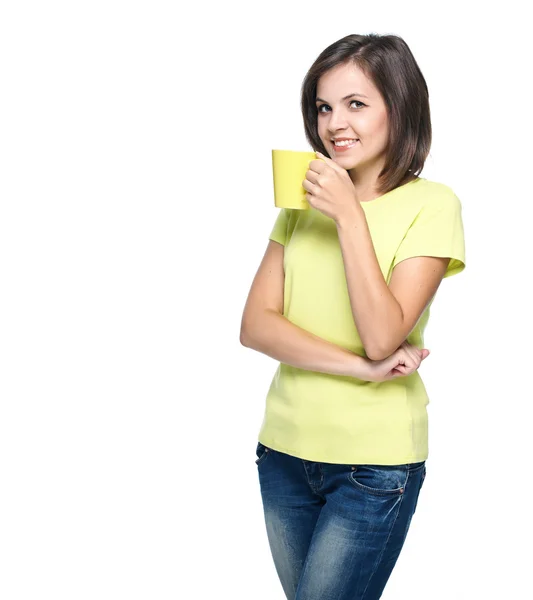 Una joven atractiva con una camisa amarilla. Sostiene un vaso amarillo . — Foto de Stock