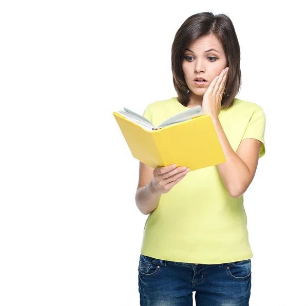 Überraschte junge Frau im gelben Hemd. liest ein gelbes Buch. — Stockfoto