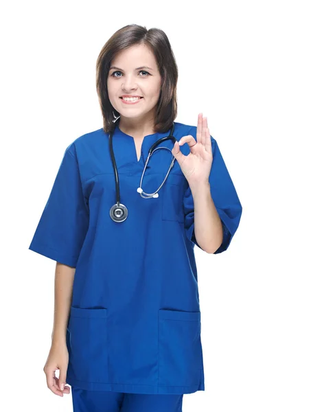 Una atractiva joven enfermera de uniforme. Muestra signo bien. Aislado en —  Fotos de Stock