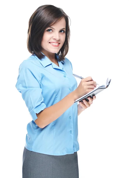 Attraktive junge Frau in blauer Bluse. schreibt in einem Notizbuch. — Stockfoto