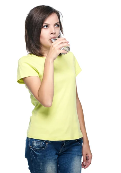 Attraktive junge Frau in gelbem Hemd und blauen Jeans. Trinken lizenzfreie Stockfotos