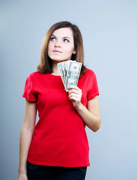 Привлекательная молодая женщина в красной рубашке. Держать доллары и гляньте — стоковое фото