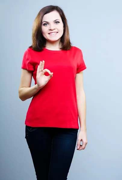 Ελκυστική νεαρή γυναίκα με ένα κόκκινο πουκάμισο. σημάδι δείχνει εντάξει. — Φωτογραφία Αρχείου