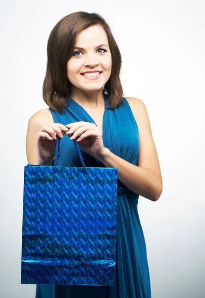 Attraktive junge Frau im blauen Kleid. hält eine Geschenktüte. — Stockfoto