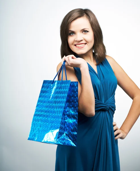 Attraktive junge Frau im blauen Kleid. hält eine Geschenktüte. — Stockfoto