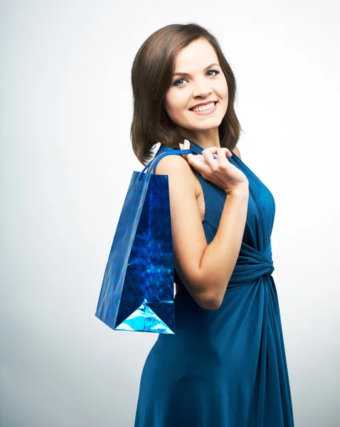 Attraktive junge Frau im blauen Kleid. hält eine Geschenktüte. — Stockfoto
