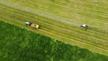 Bavyera 'daki bir çayırda saman toplayan iki traktörün insansız hava görüntüsü.