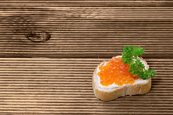 Sandwiches con caviar rojo sobre tabla de madera —  Fotos de Stock