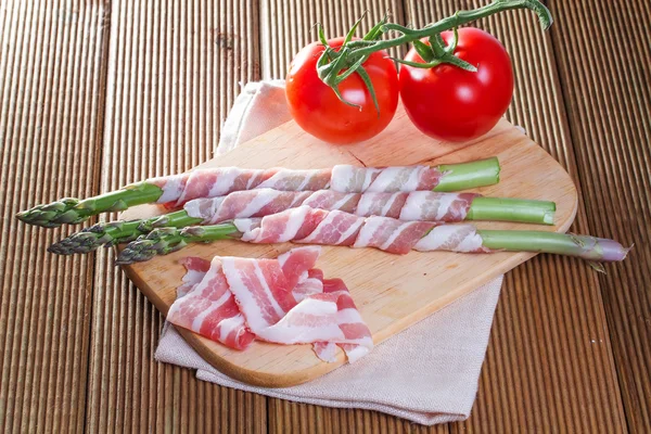 Bacon and asparagus on a wooden background — Stock Photo, Image