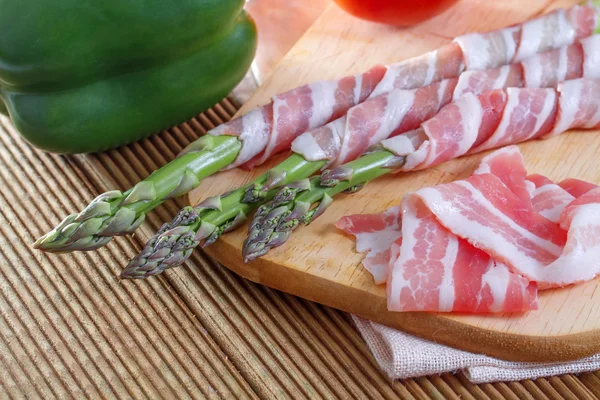 Bacon and asparagus on a wooden background — Stock Photo, Image