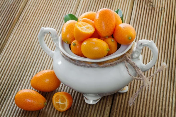 Ripe kumyauat with leaves in a bowl — Stock Photo, Image