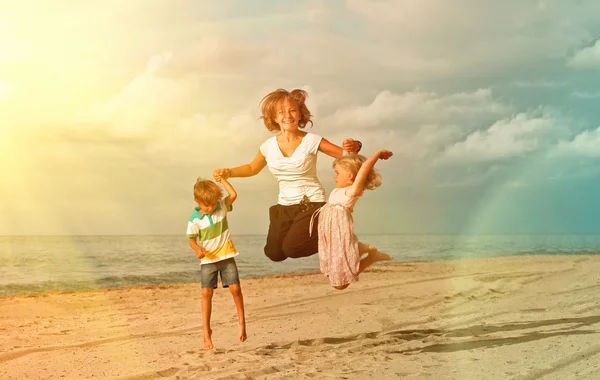 孩子们在日落时在海洋沙滩上跳跃 — 图库照片