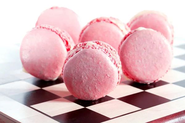 Pink French macarons on a chessboard — Stock Photo, Image