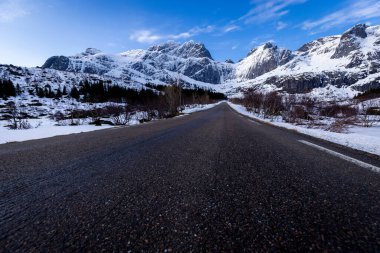 Snowy road to the mountains at winter with sunny weather with blue sky