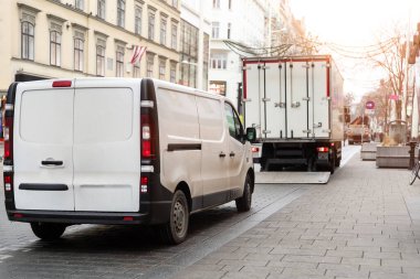 Küçük beyaz minibüs ve orta büyüklükteki kargo kamyonu Avrupa 'nın eski şehir caddesine park edilmiş. Hızlı ekspres kurye servis konsepti. Taşıma ve nakliye lojistik dağıtımı emri