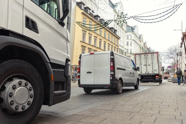 Small white van and mid size cargo truck parked for unloading at european old city street road. Fast express courier delivery service concept. Moving and orders shipping logistics distribution